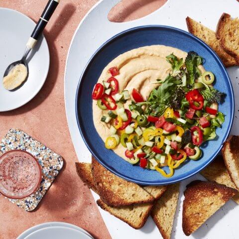 A blue bowl with dip and bread chips photographed from above.