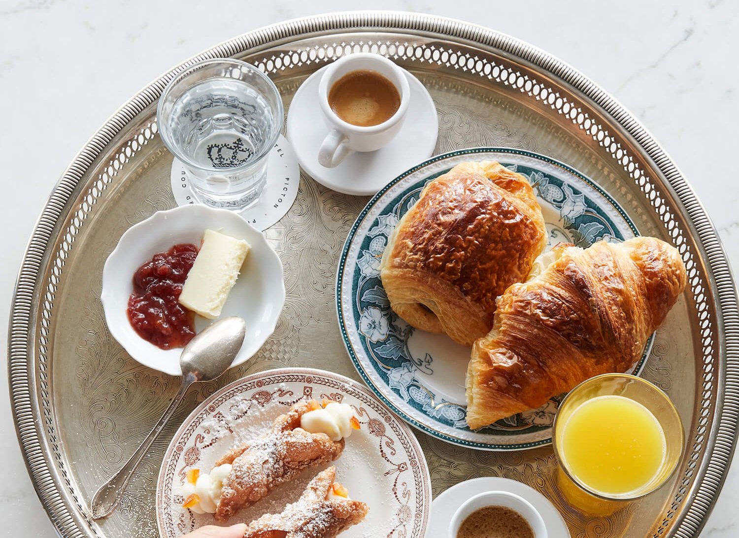 A silver tray laid with pastries, coffee and juice