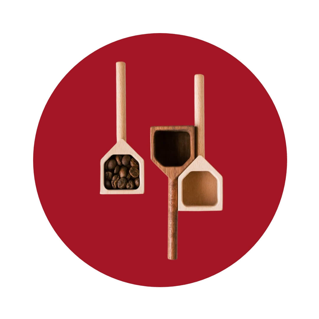 Three small wooden scoops shaped like houses, one filled with coffee beans, on a red circle graphic.