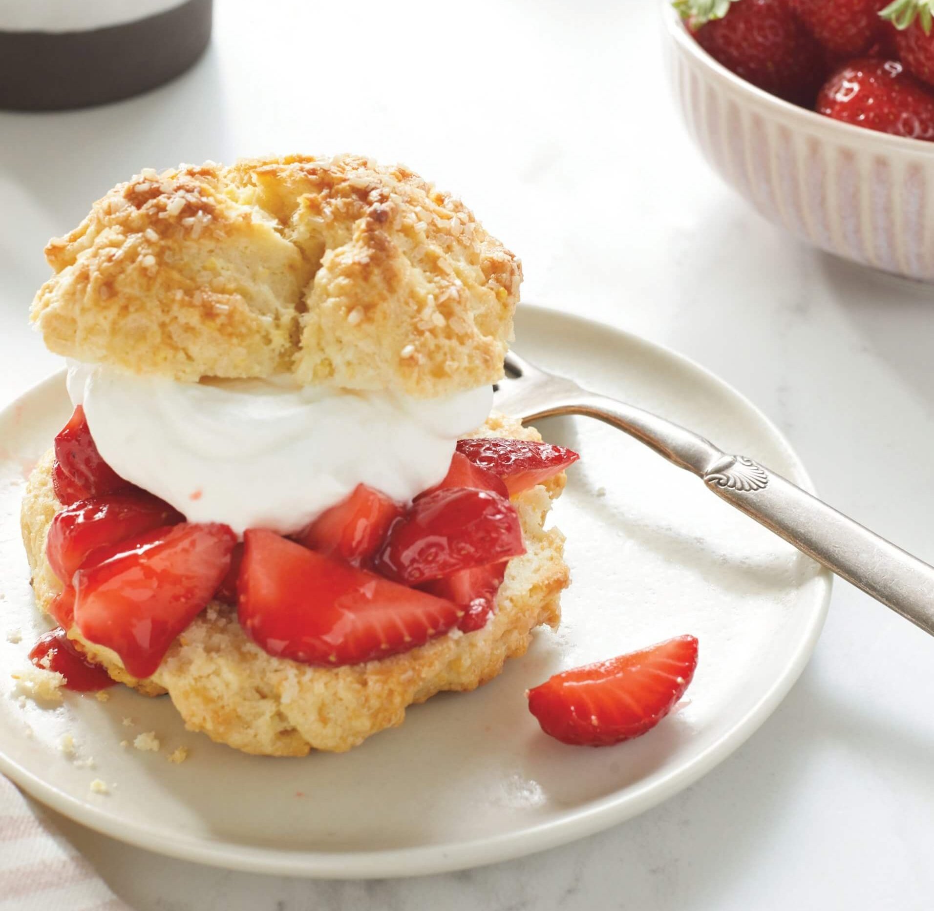 A white plate with a strawberry shortcake and more servings visible in the background.