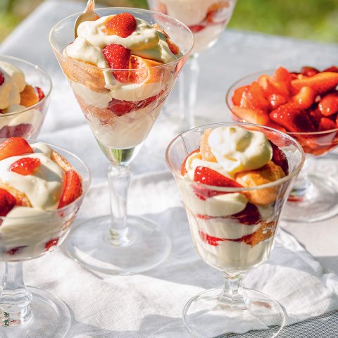 A white cloth on grass laid with strawberry parfaits