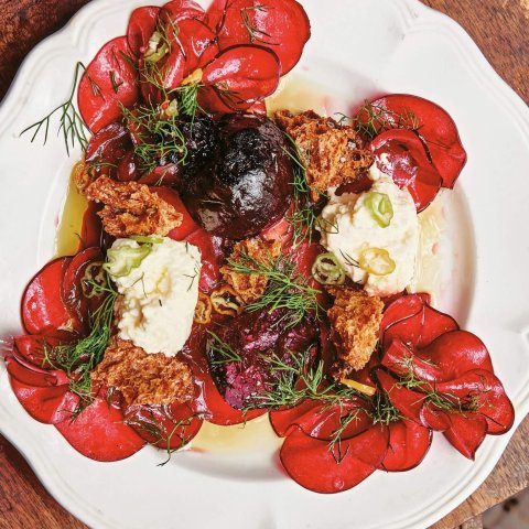 A white plate with a colourful beet salad on a wooden table