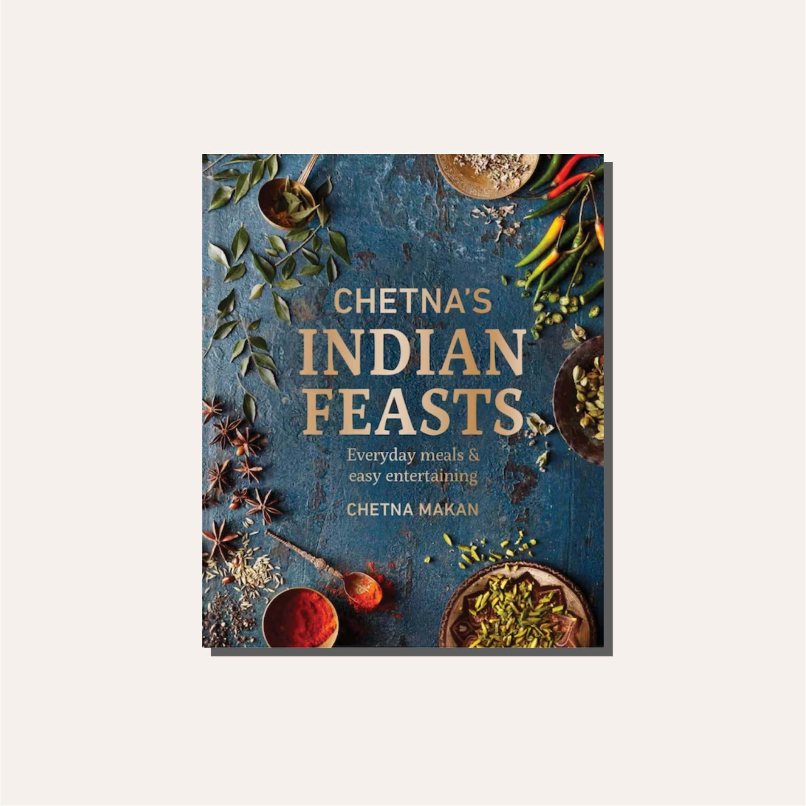 A teal blue cookbook titled "Chetna's Indian Feasts" in a light tan frame