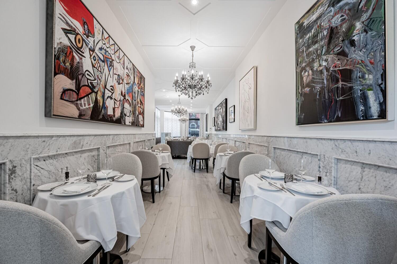 A white dining room with colourful abstract art on the walls