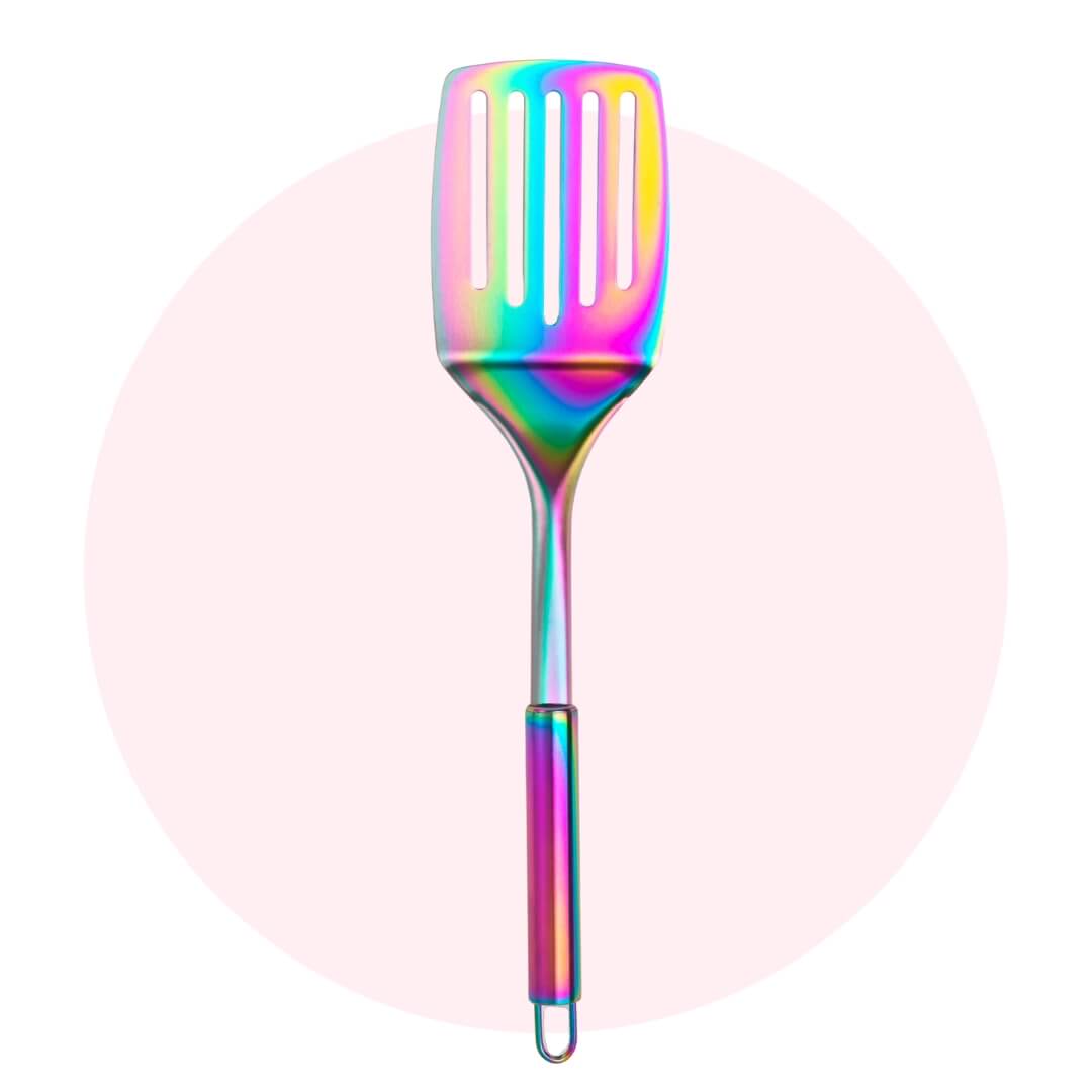 A oink-heavy rainbow metal cooking spatula on a light pink circle graphic