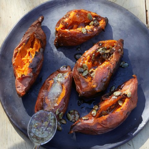 A dark blue dish with roasted sweet potatoes and a spoon visible