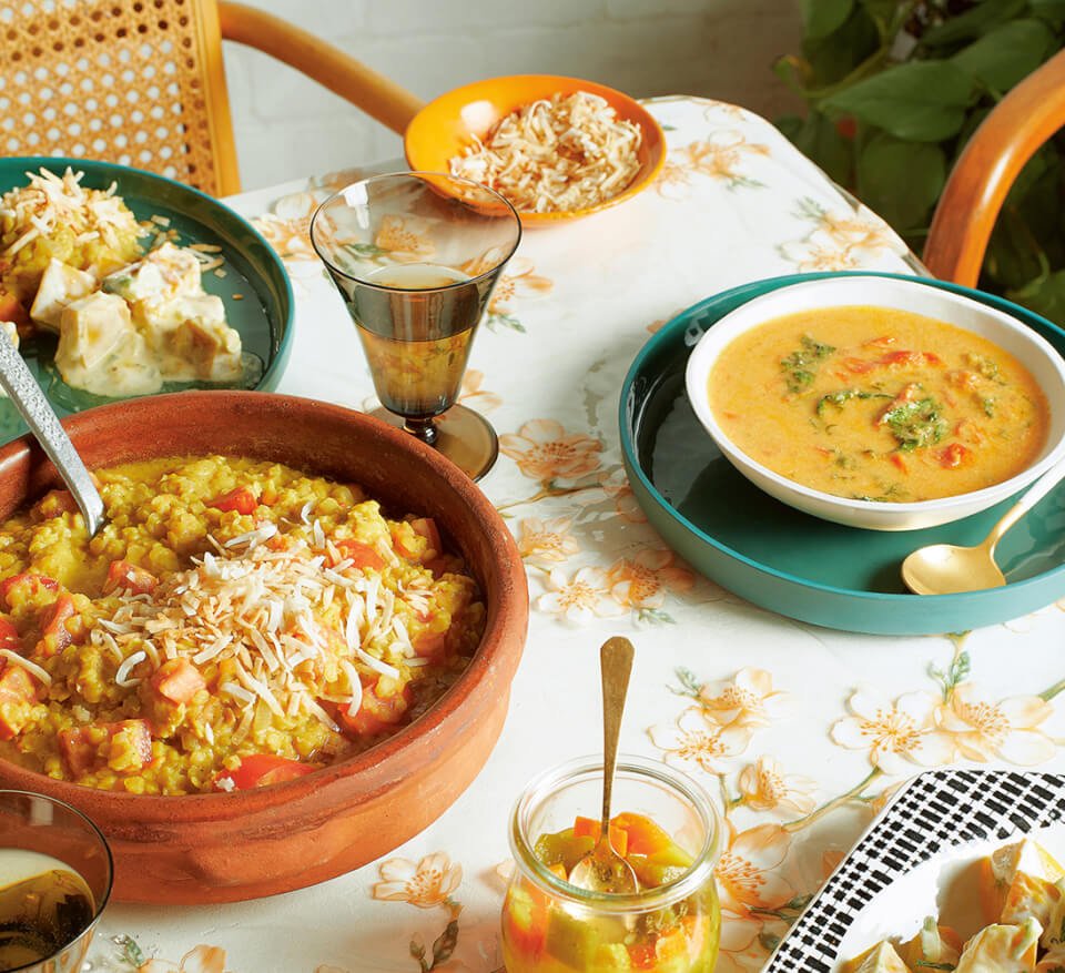 A table with a floral tablecloth and multicoloured dishes with rice and curry