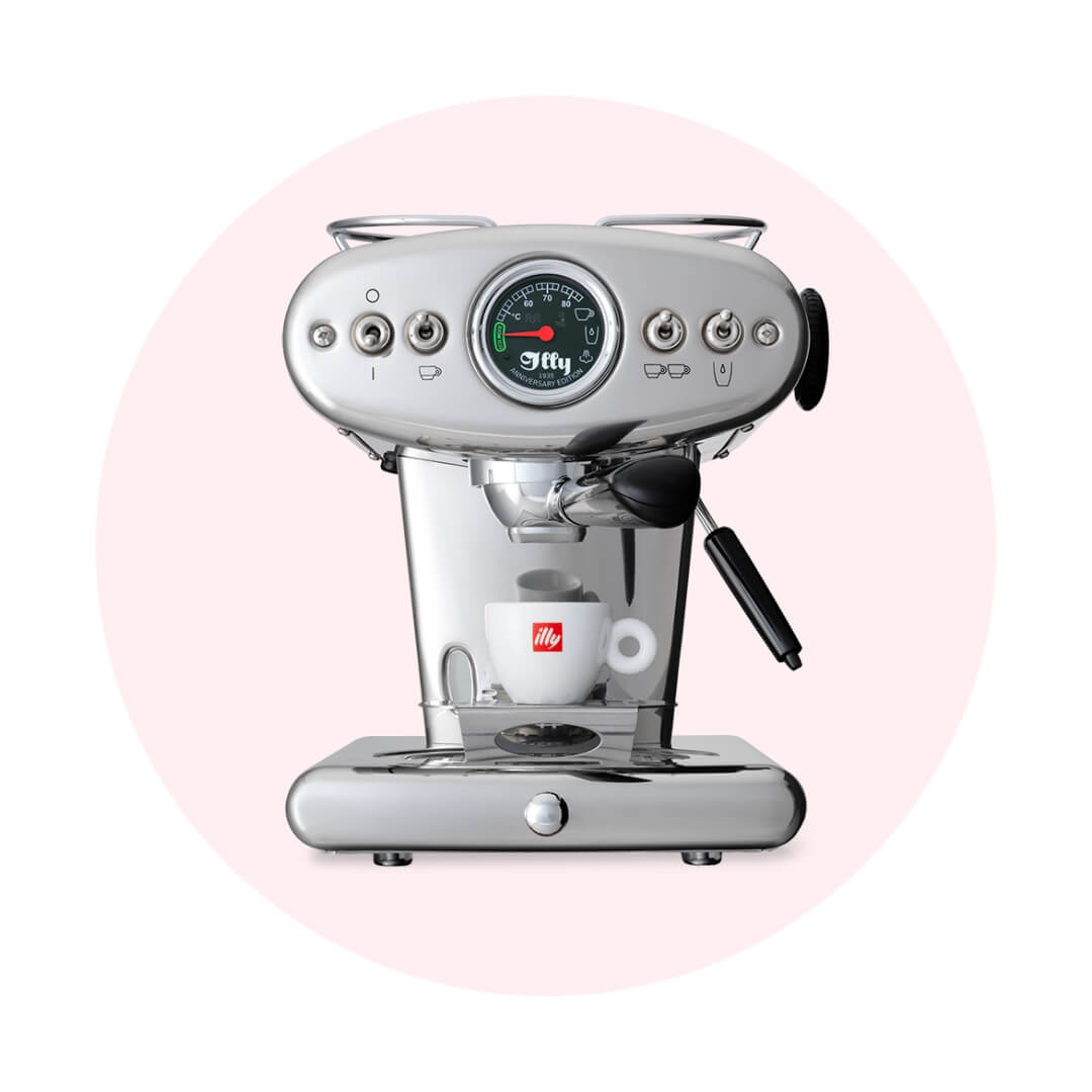 A silver Illy coffee machine over a pale pink circle graphic