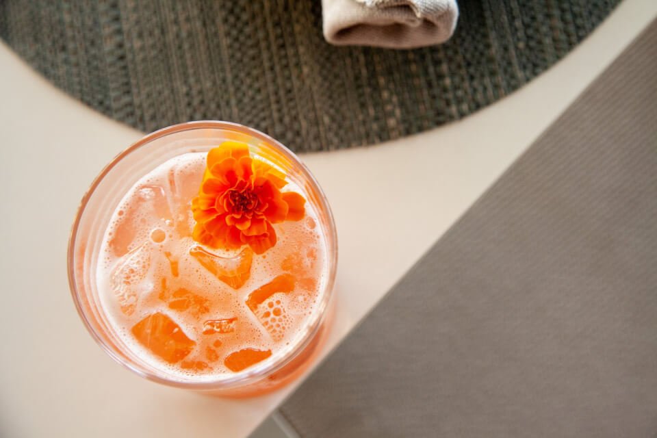 An orange cocktail with a flower garnish