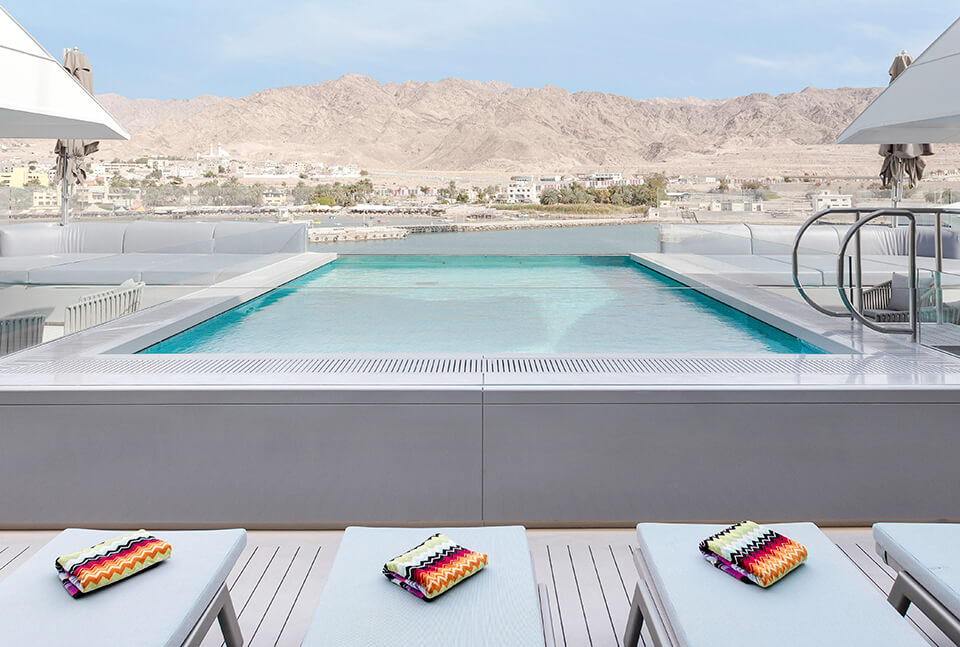 swimming pool with towels in foreground and mountains in back