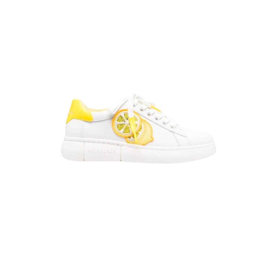 A white sneaker with yellow detailing and a lemon applique