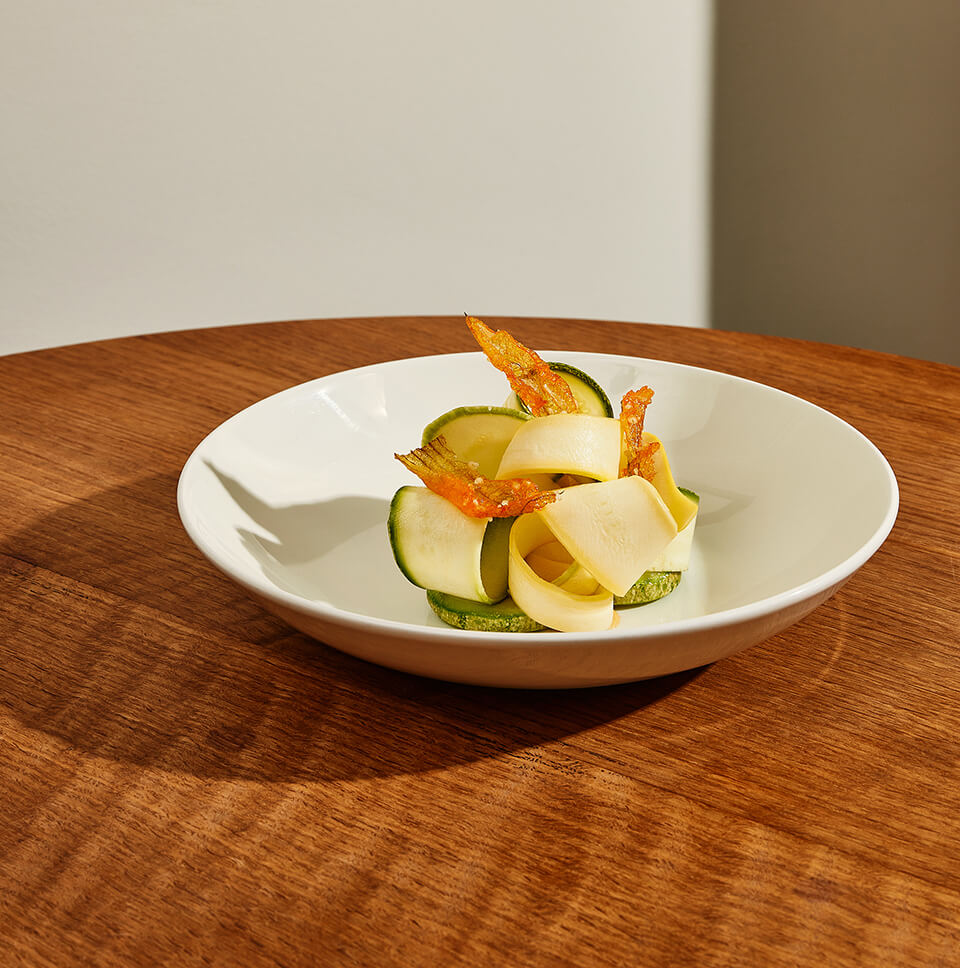 A white dish with food on a wooden tabletop