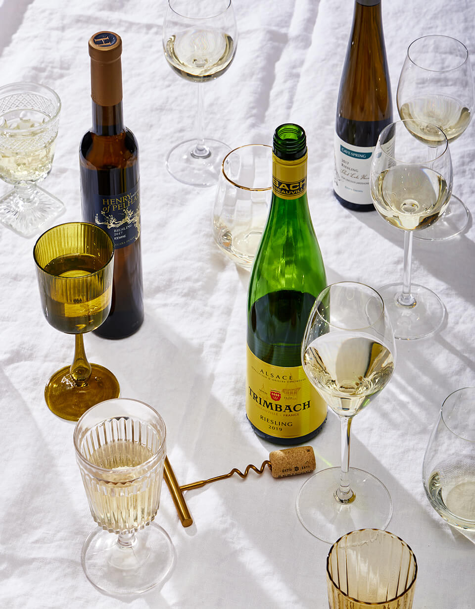 Various bottles of Riesling with assorted glasses on a white tablecloth