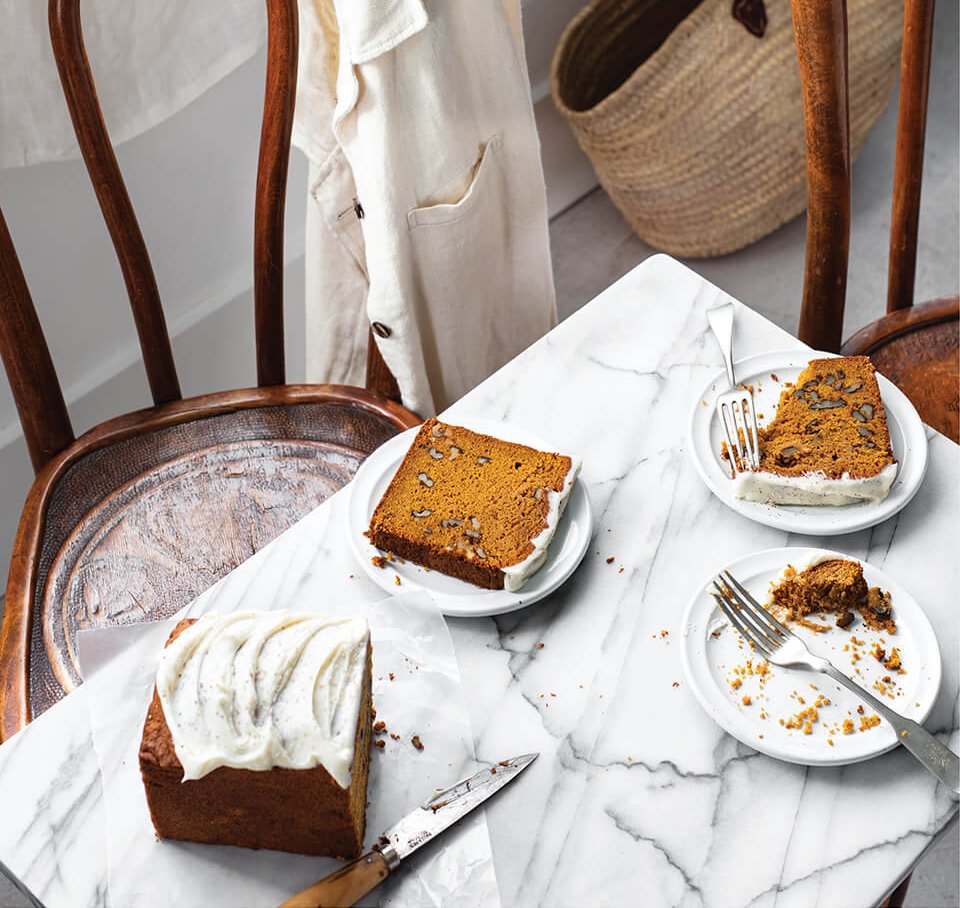 A table and wooden chairs with plates of pumpkin load with white frosting