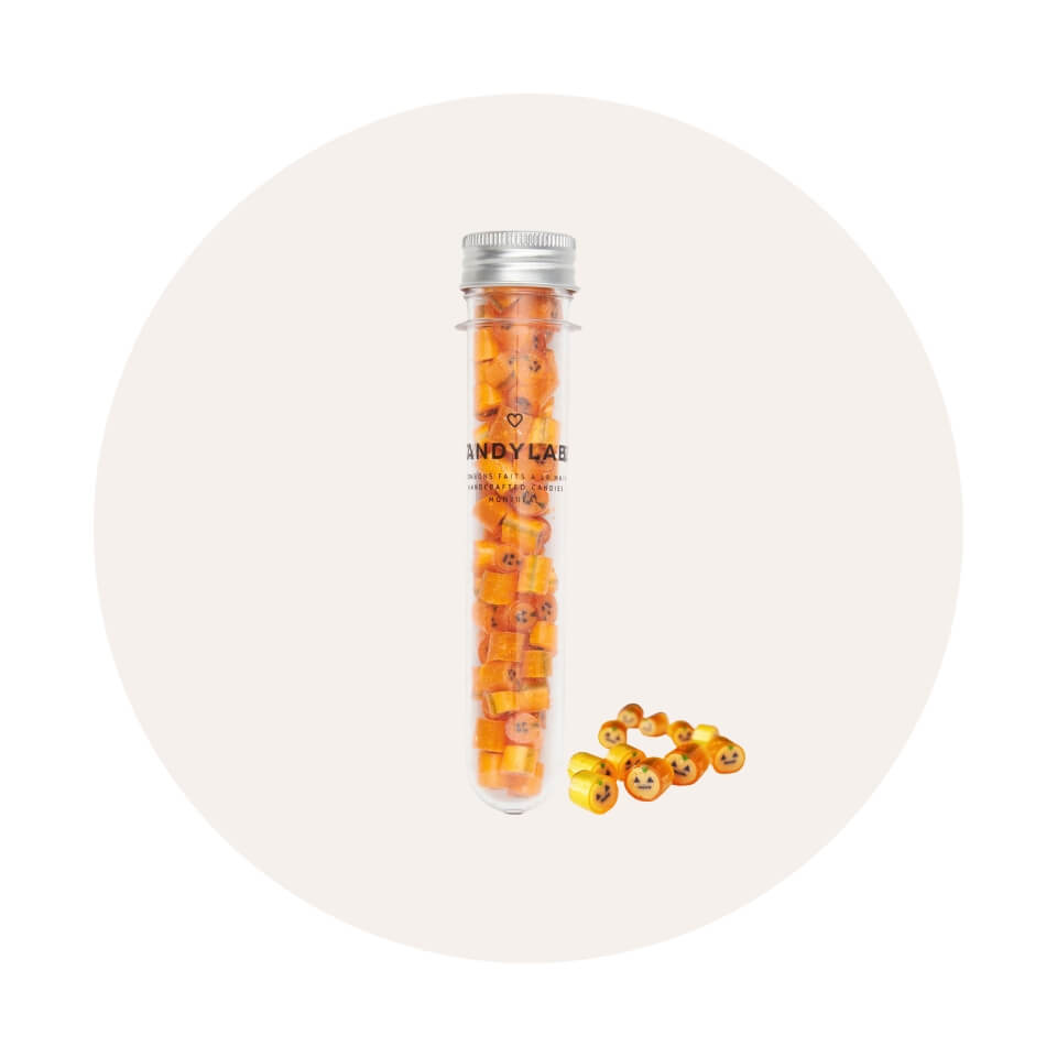 A vial of orange candies on a white circle