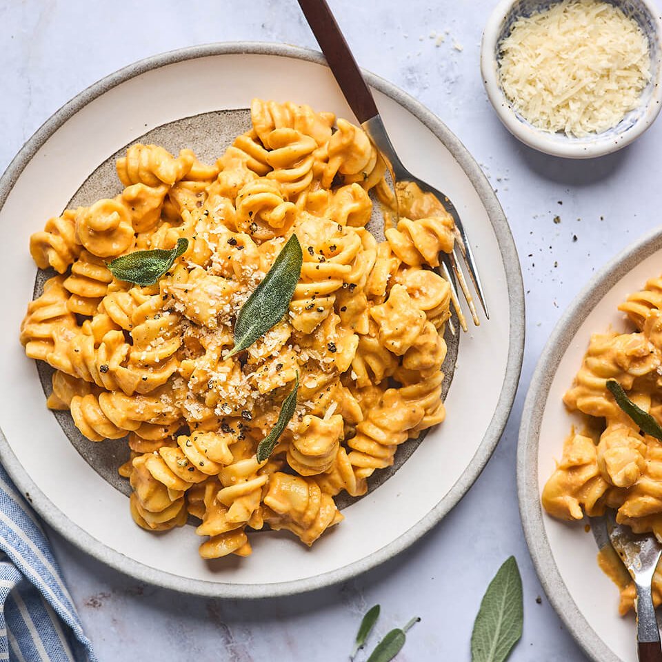 A white plate with rotini in an orange pasta sauce