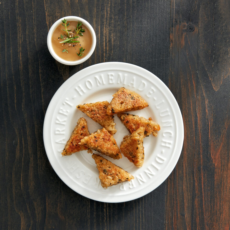 A white plate with croutons and a ramekin of dipping sauce