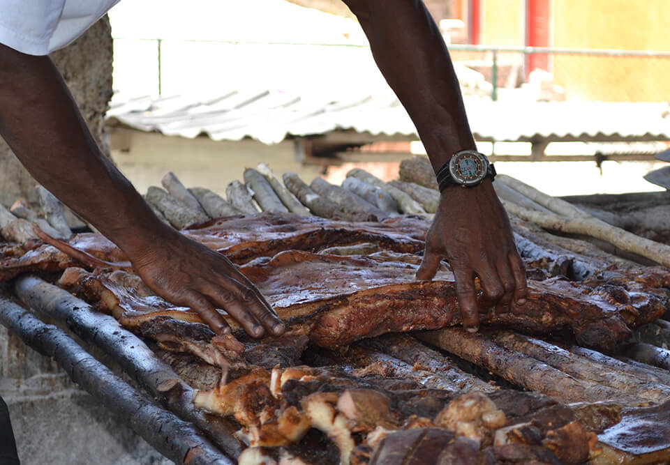 A man preparing jerk chicken to cook outdoors