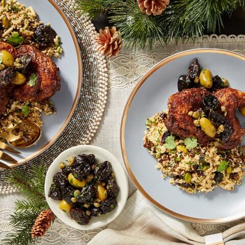 Dishes with couscous and chicken amidst Christmas table decorations