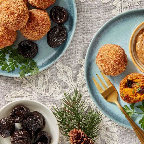 Light blue dishes with pine needle fronds next to them and fried fritters being served