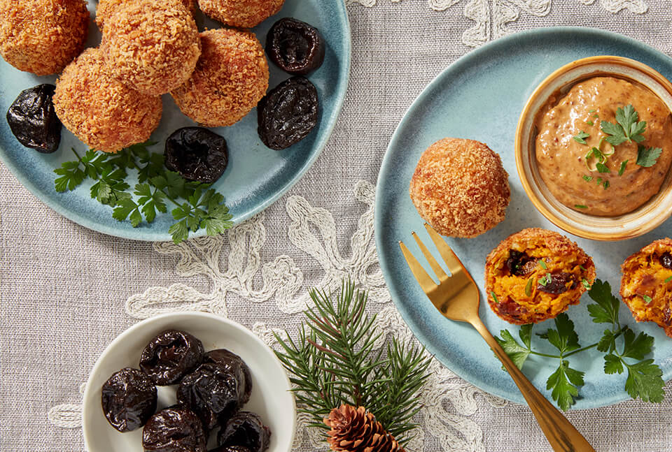 Light blue dishes with pine needle fronds next to them and fried fritters being served