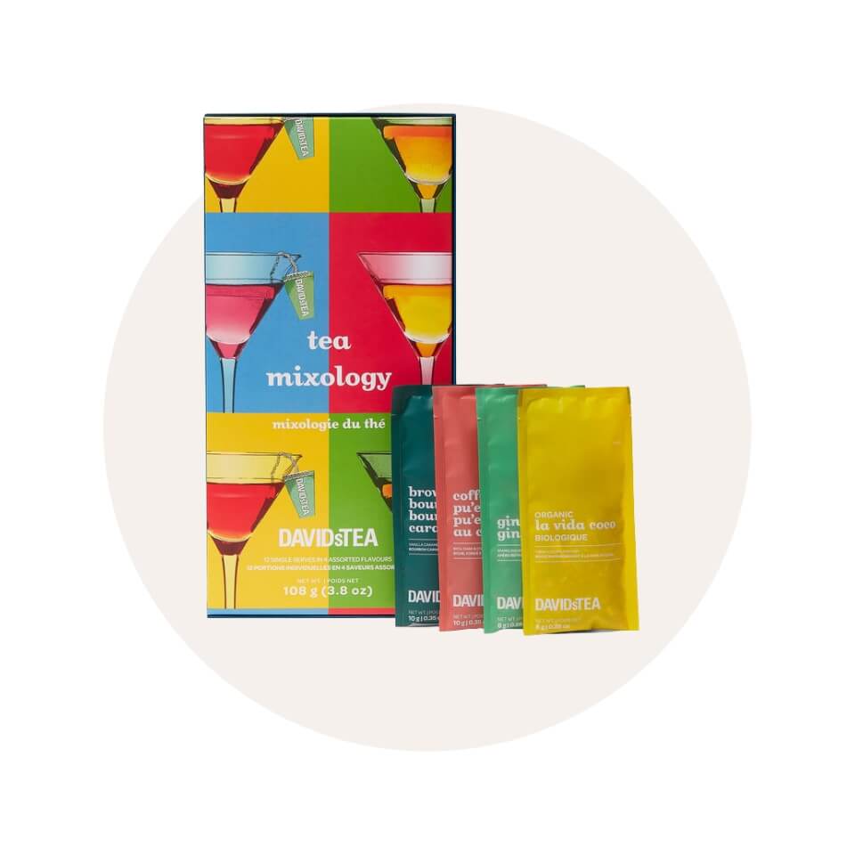 A multicoloured gift box and four sachets of tea over a cream-coloured circle