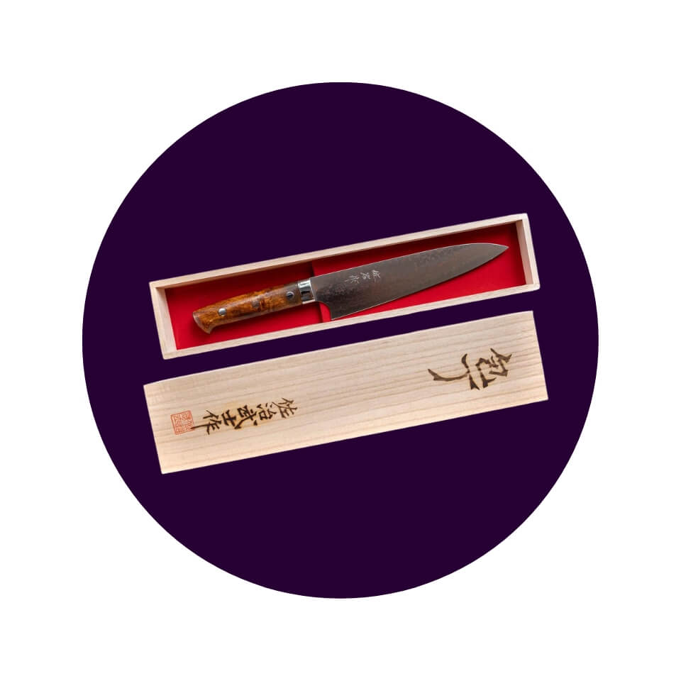 A wooden box with red lining holding a kitchen knife inside a dark purple circle