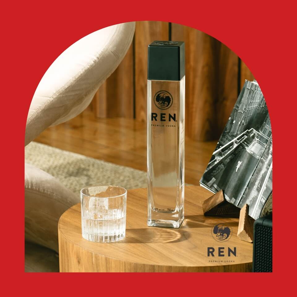 A bottle of vodka and a glass on a short wooden table