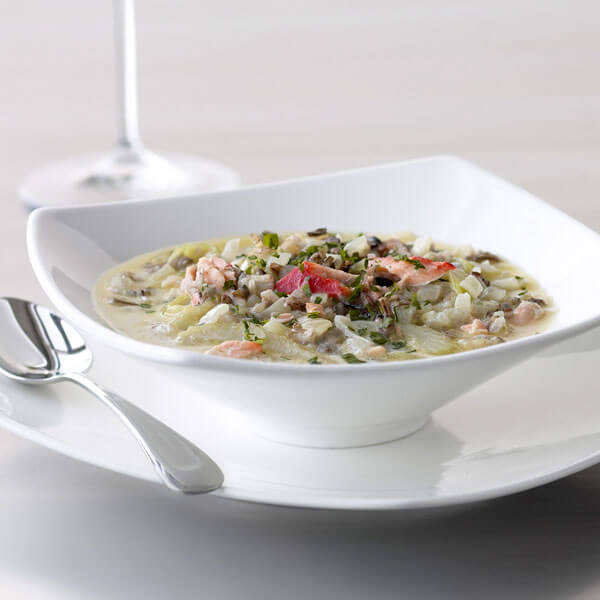 A white bowl of soup on a plate