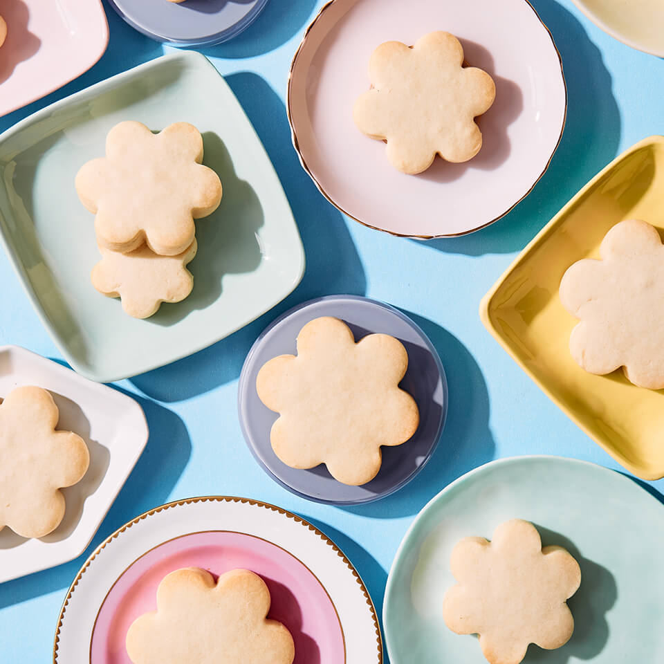 Shortbread cookies on a flower shape on plates of various colours on a blue table