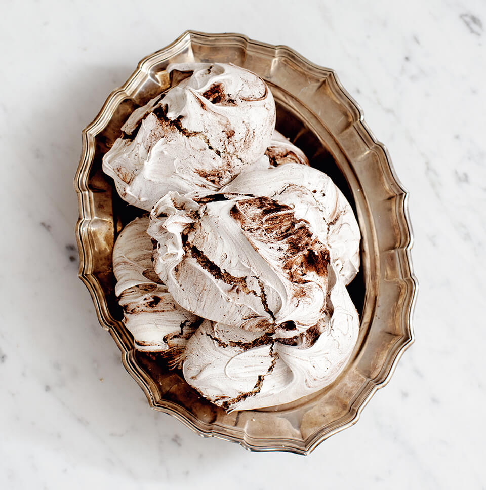 A plate with chocolate meringues on a white marble surface