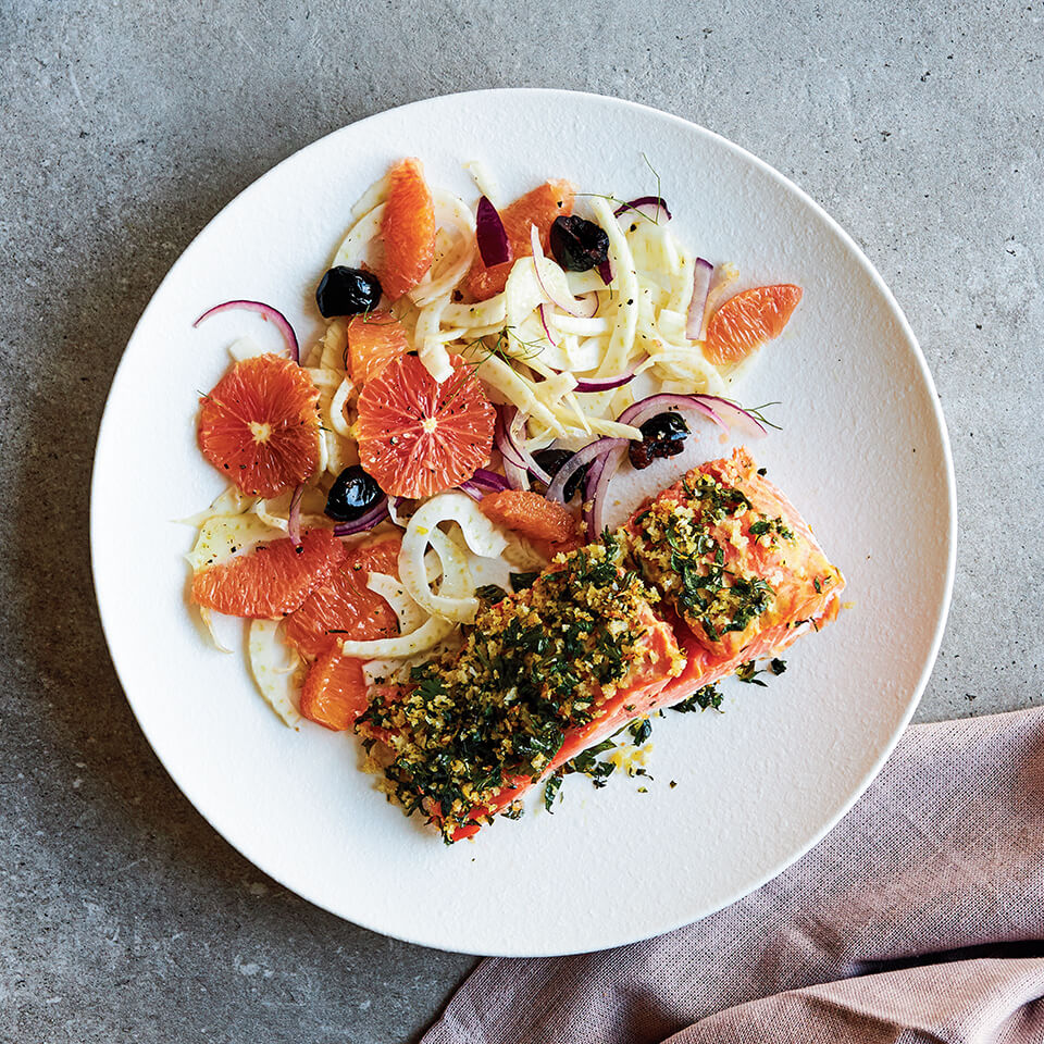 A white plate with grematola-crusted salmon and salad