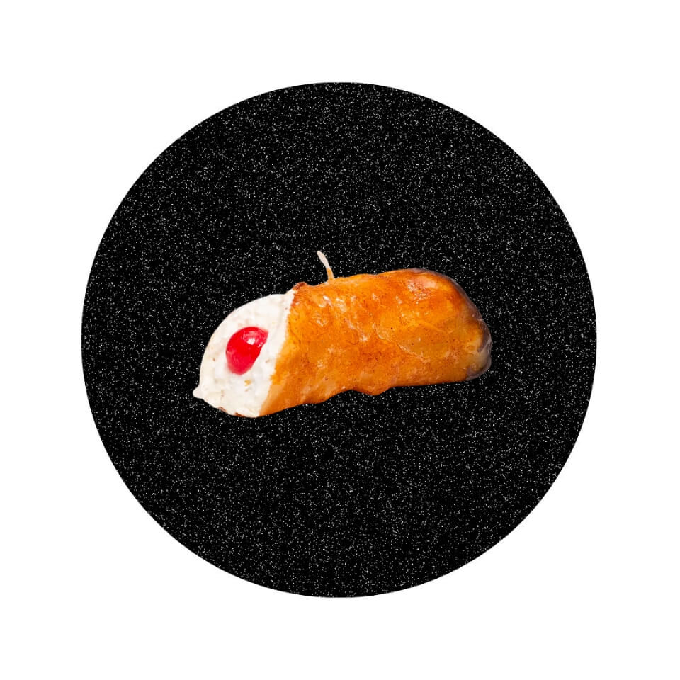 A candle shaped like a cannoli in a sparkly black circle