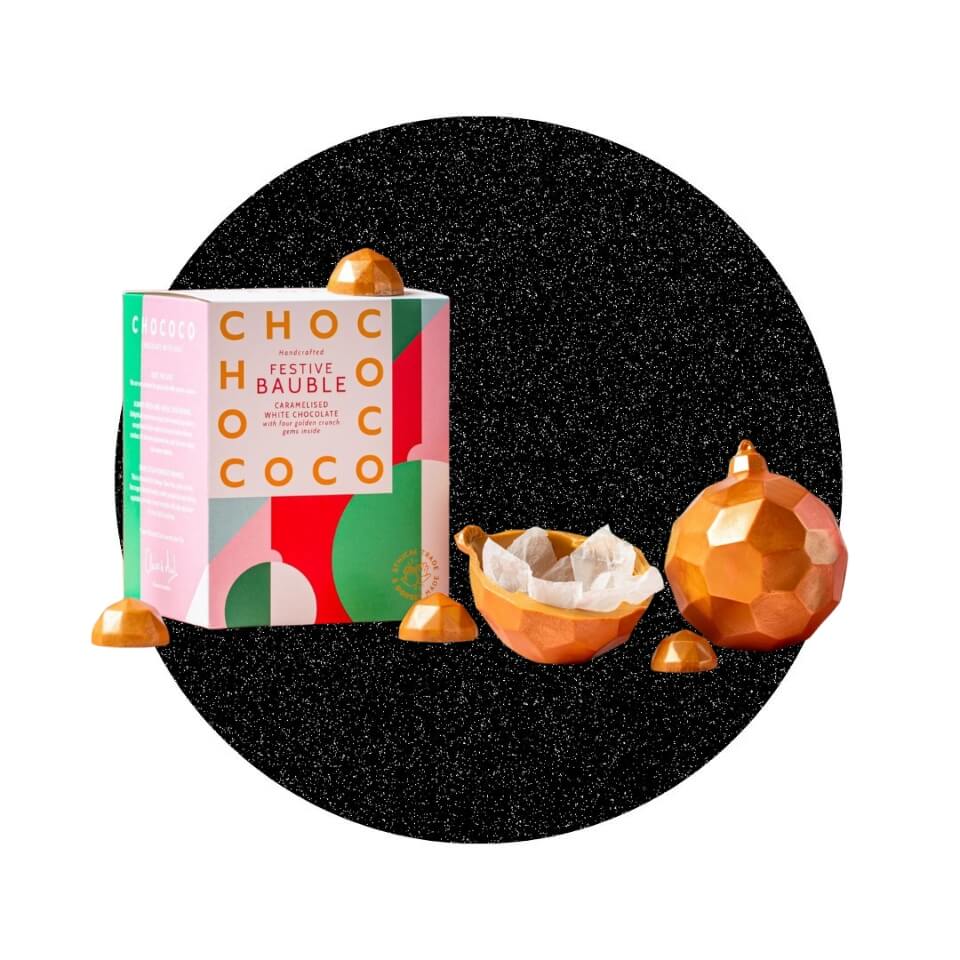 A chocolate Christmas ornament and decorative box over a sparkly black circle