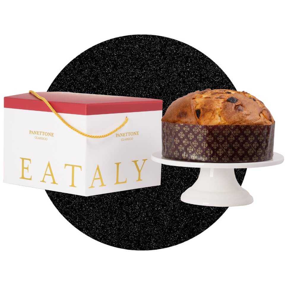 A panettone on a white cake stand and a box with a red lid over a sparkly black circle