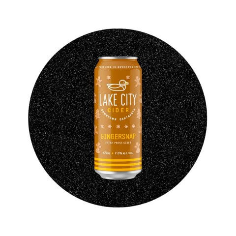 An orange can of cider in front of a decorative black circle.