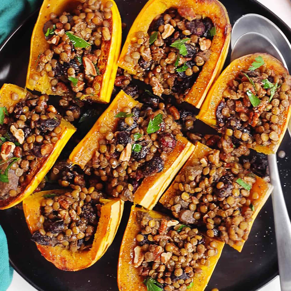 A black plate with stuffed squash halves and a blue napkin visible on the edges