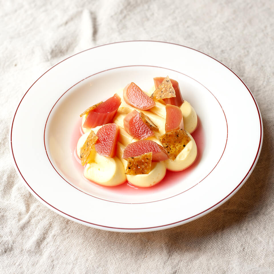 A white dish with a rhubarb dessert on a white tablecloth