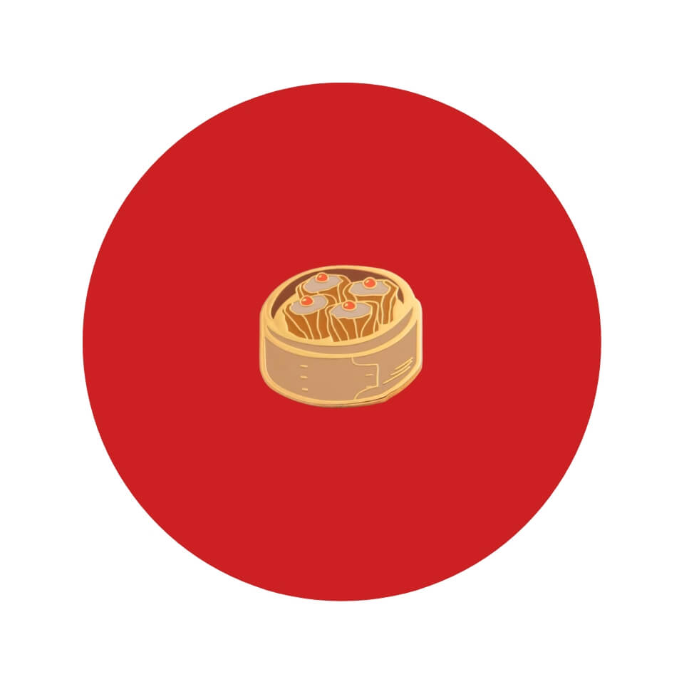 An enamel pin shaped like a wooden steaming basket filled with shumai in a red circle