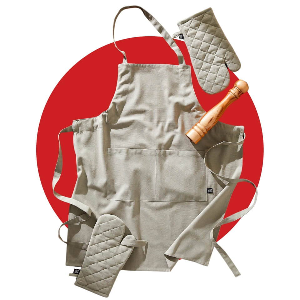 A light apron, two oven mitts and wooden pepper mill over a red circle