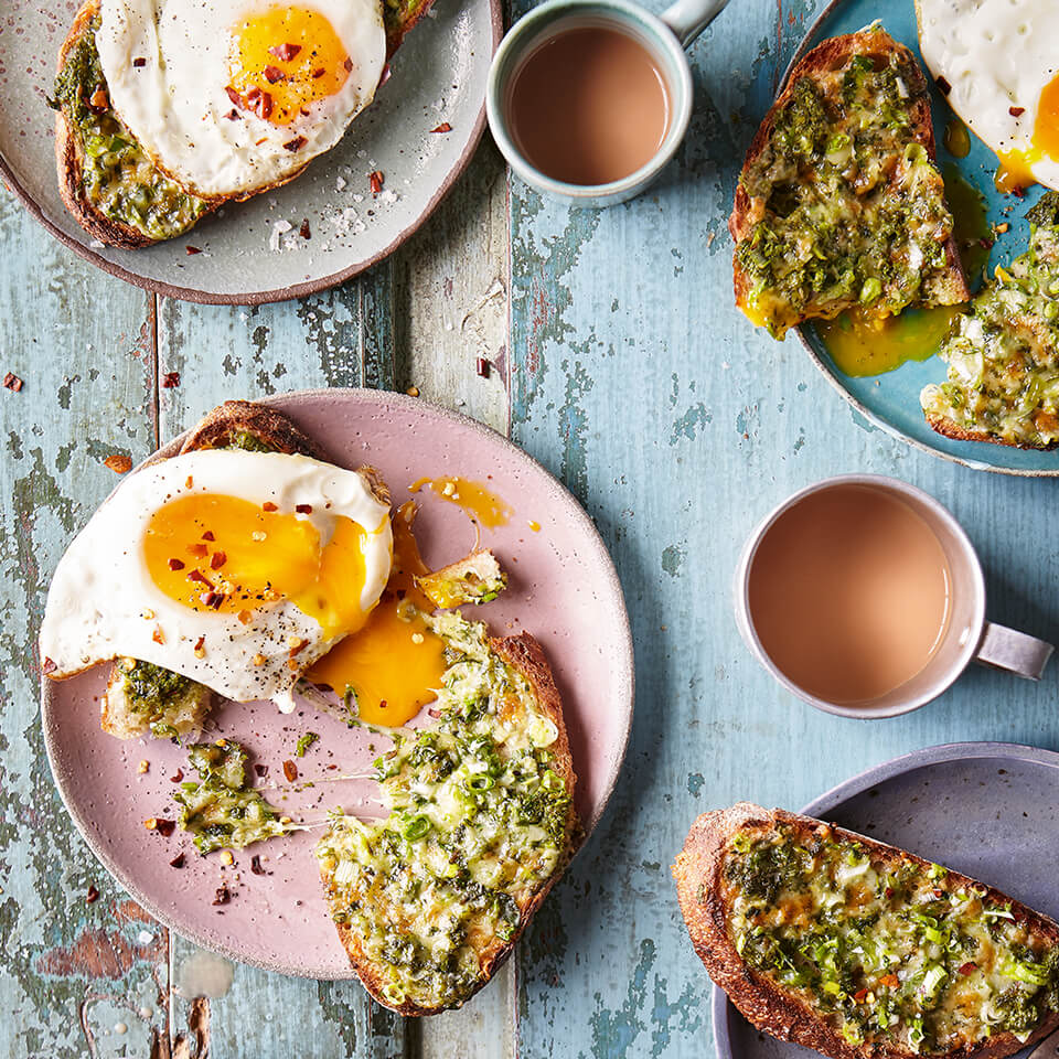 Plates of toast with eggs and avocado spread, with cups of tea