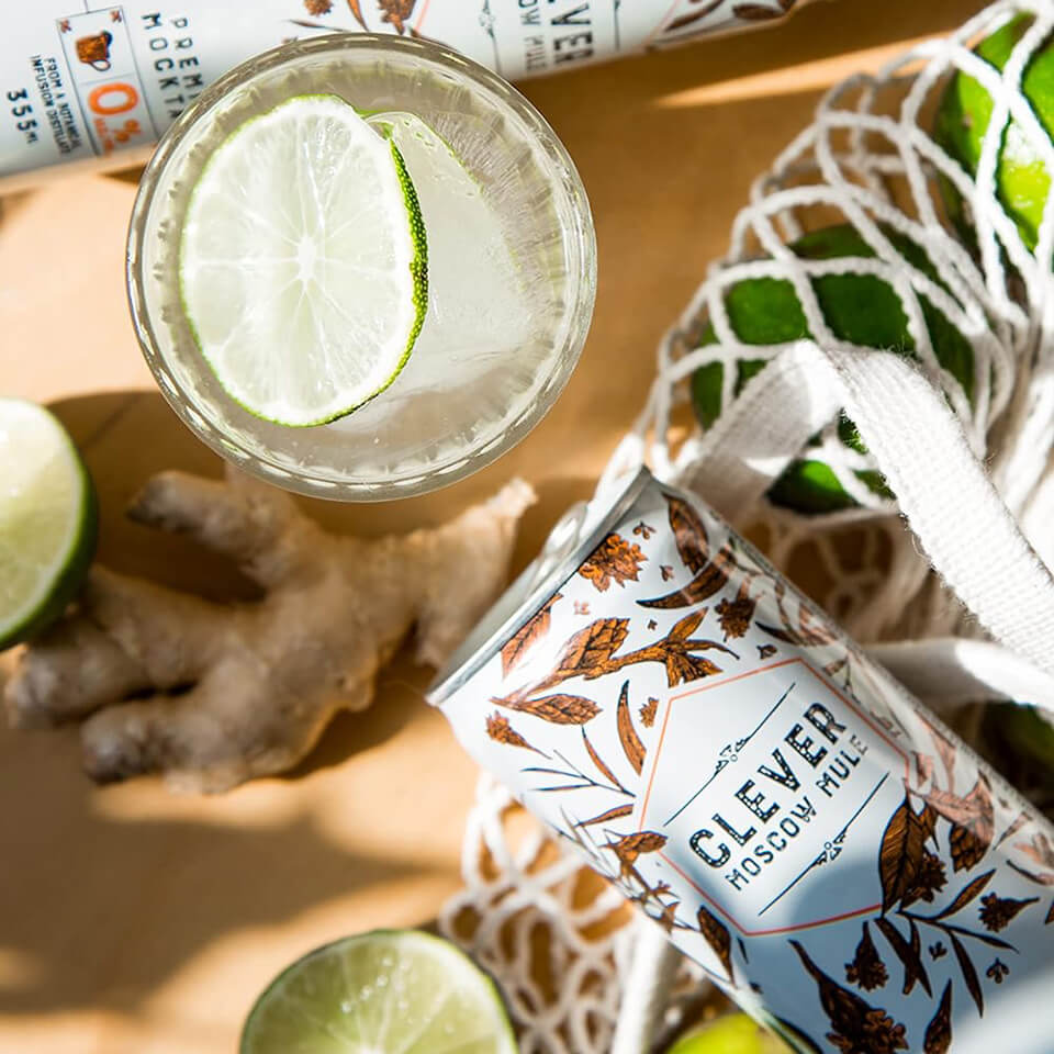 A canned cocktail, glass with lime and mesh bag filled with limes photographed from above