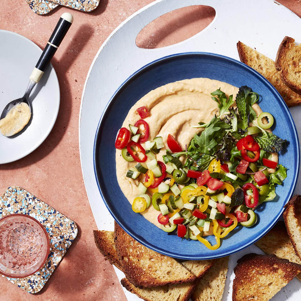 A bowl with bean dip and pita crackers 