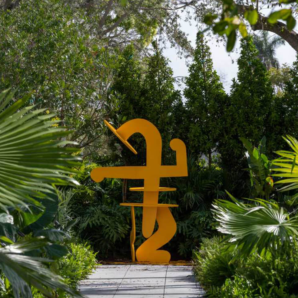 A yellow sculpture surrounded by plants