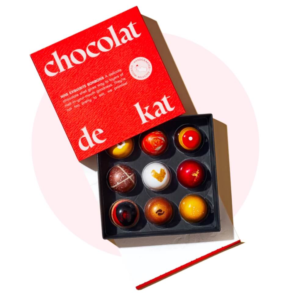 A box of chocolate with a bright red lid over a light pink circle