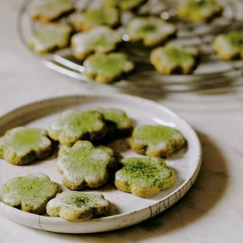 A plate with flower-shaped cookies dusted with matcha tea