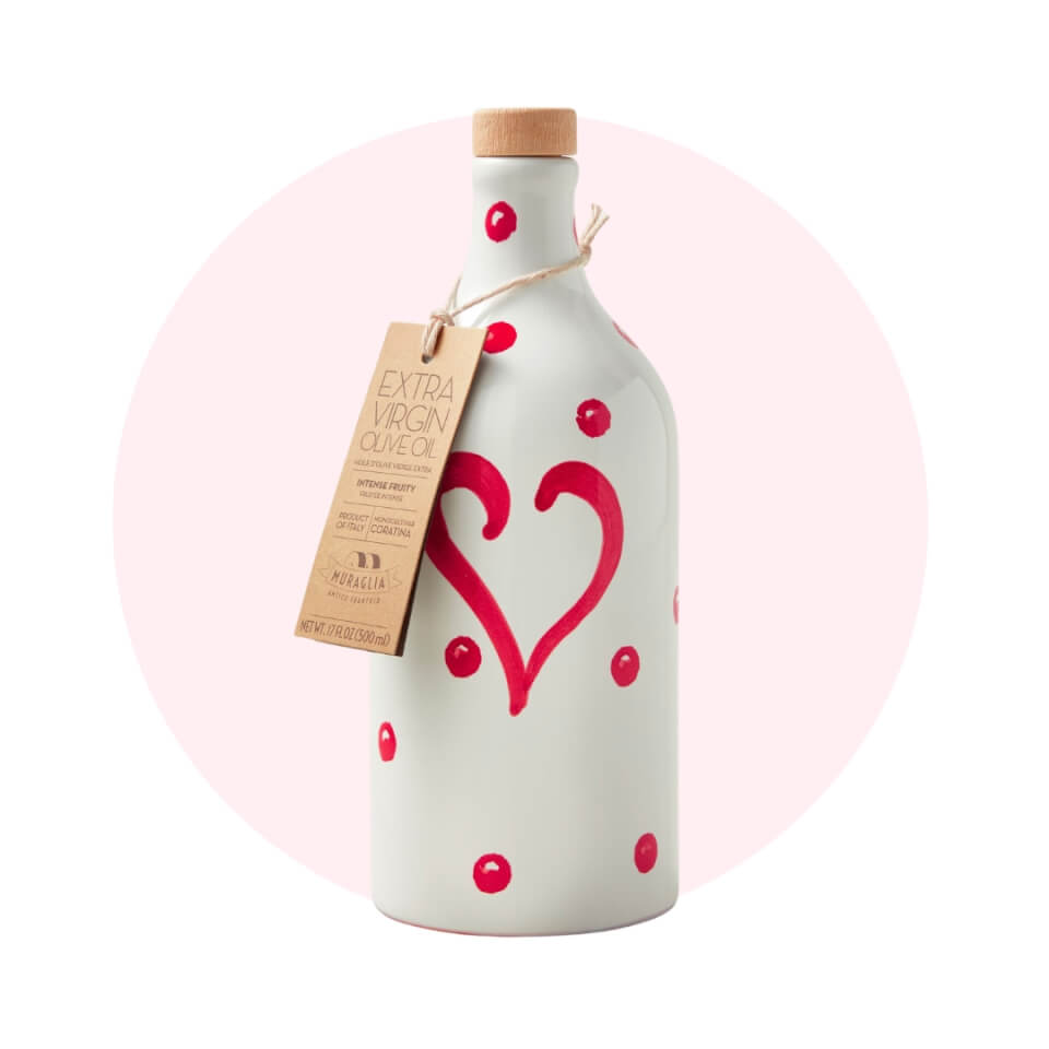 A bottle of olive oil with hearts on in over a light pink circle