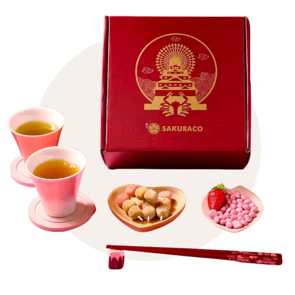 A red box, two cups of tea and some snacks over a white circle