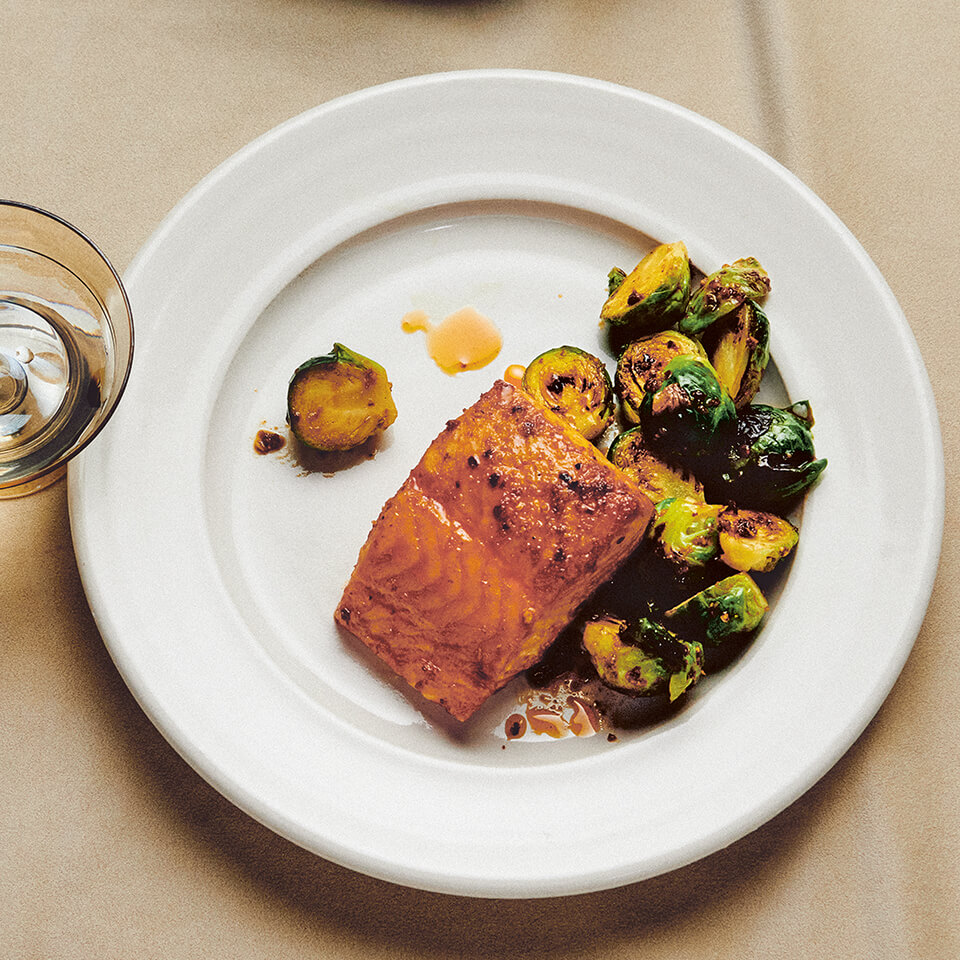 A white plate with salmon and Brussels sprouts