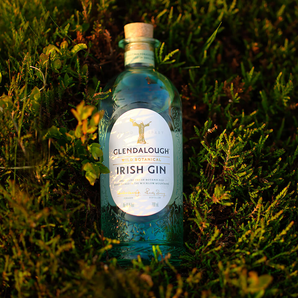 A bottle of gin nestled in plants outdoors